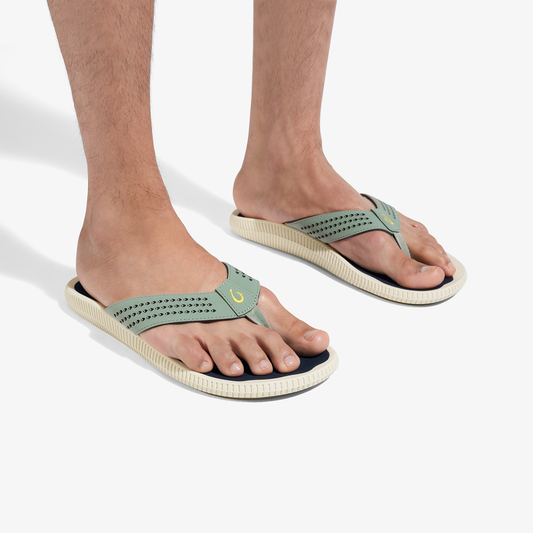 Seagreen and cream thong sandals with perforated straps and textured soles, worn on bare feet.